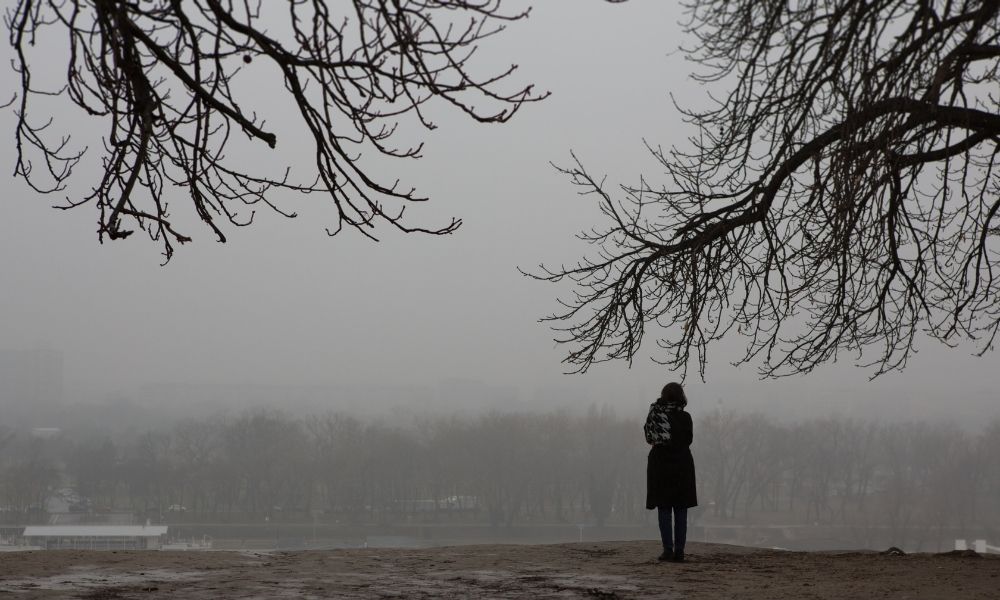 A lone woman in the gloomy dark of early winter.