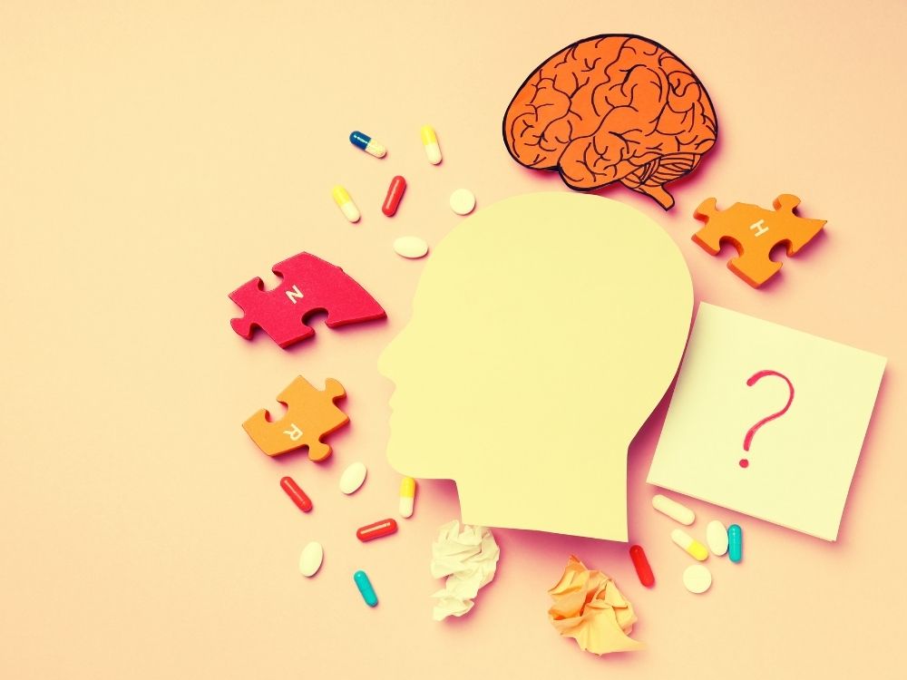 1000 x 750 A cut out head-brain surrounded by various puzzle pieces, medications signifying the symptomology of toxic stress and trauma.