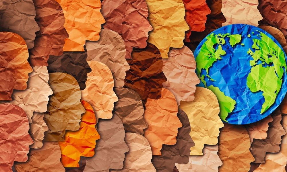 An assortment of human heads cut from different coloured paper alongside the world depicting the importance of diversity when thinking about stress and its impact.