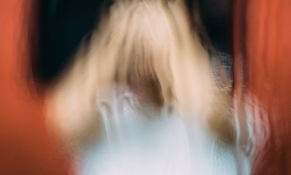 A distorted image of a human holding their hands on their heads seemingly distressed signifying the challenges of struggling with and recognizing toxic stress and trauma.