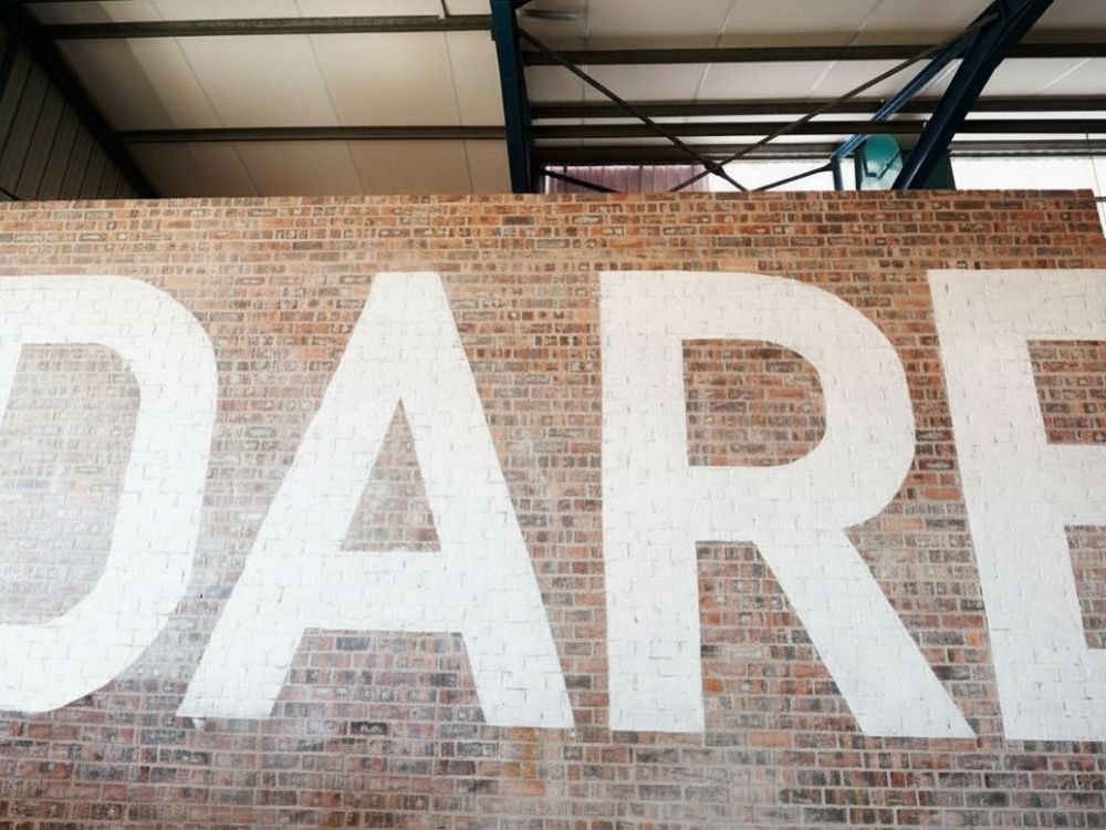 1000 x 750 A large brick wall with the word "DARE" in big letters.